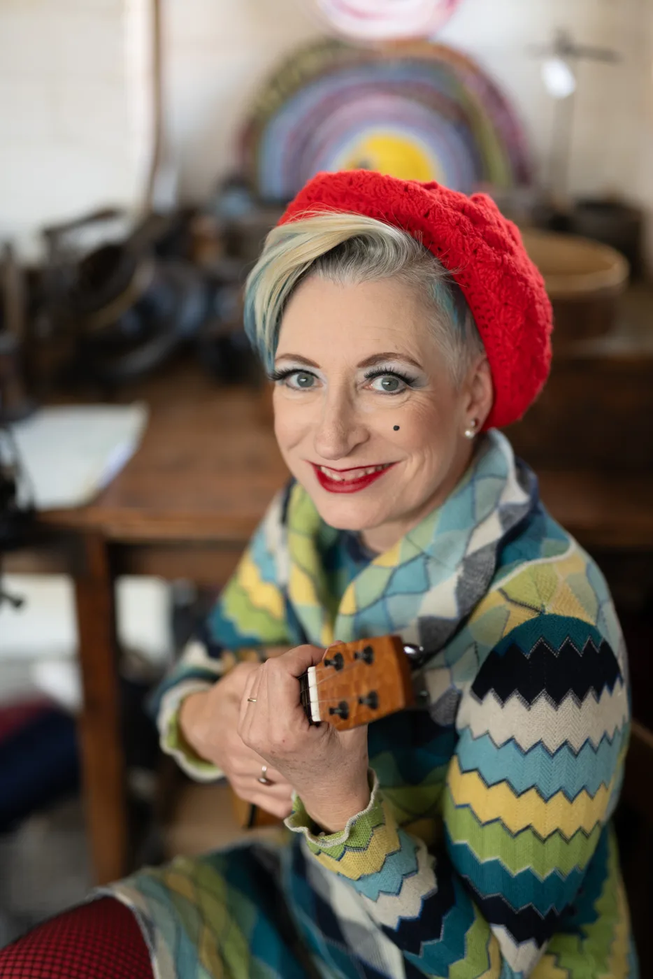 Tricity Vogue in a red beret and zigzag knitted dress, holding a ukulele