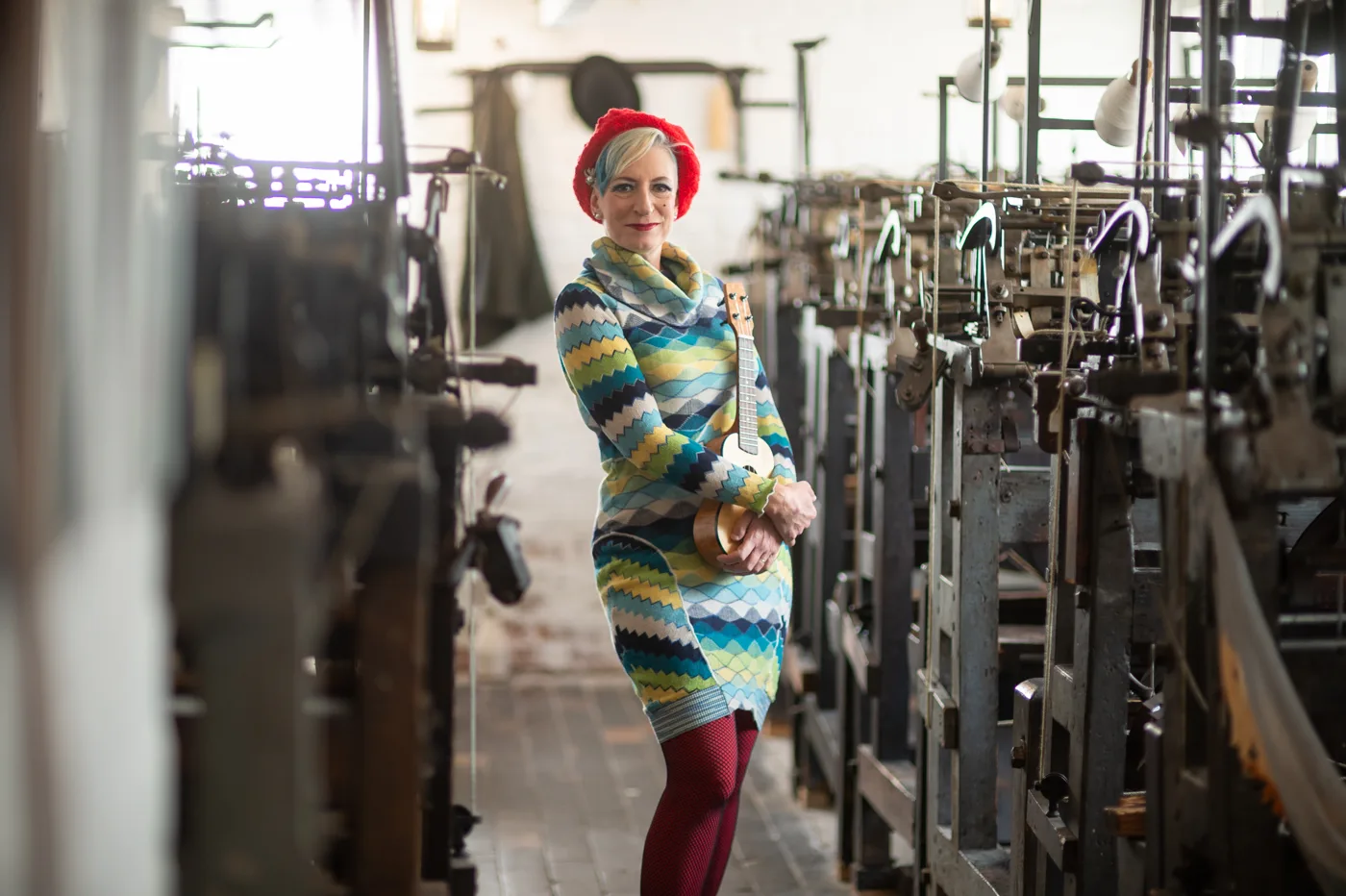 Tricity Vogue walking between rows of old knitting frames at the museum