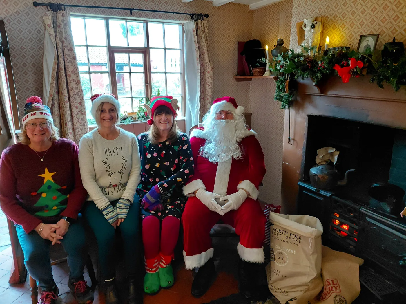 Father Christmas with three helpers in elf hats beside the range in one of the museum's Victorian workers' cottages
