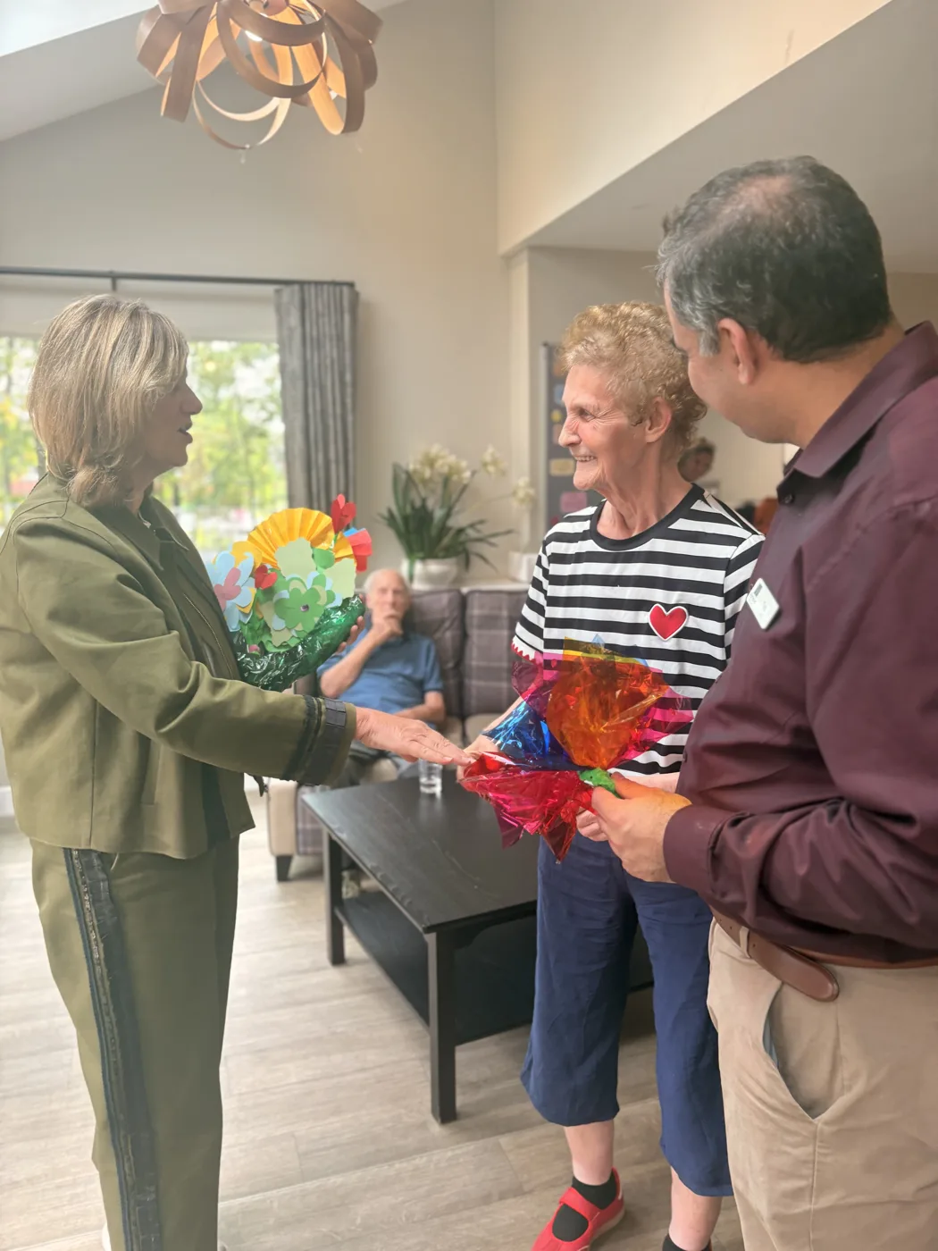 Lilian Greenwood MP and home manager Tabish Syed with a Wilford View resident who is holding a colourful handmade paper bouquet